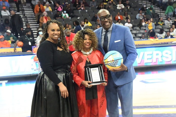 Maxine Lewis, DSU Class of 1973, shows her 2023 Distinguished Alumnae award while standing with the presenters MEAC Commissioner Sonja Sills and MEAC corporate partner Timothy Rodgers of TIAA Insurance Co.