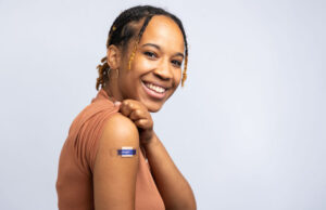 Los beneficios de la vacuna contra el COVID-19 superan los riesgos, contrariamente a afirmaciones erróneas de un cardiólogo británico Mujer joven sonriendo al recibir los beneficios de la vacuna contra el Covid-19