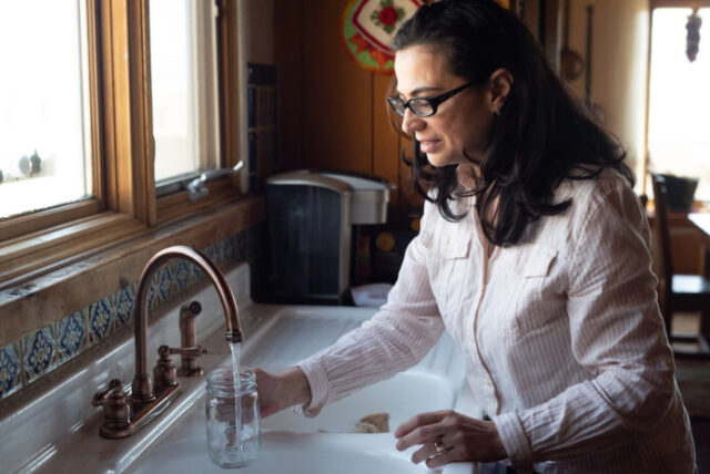 Mujer sacando agua de su grifo luego de que las autoridades señalaran que el agua fluorada es segura.