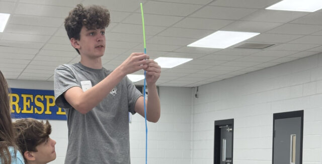 Photo: Students placing the final touches on their Team Survival Shelter Challenge. Standing and holding straws: Jacob Bush (Photo courtesy Sussex Technical HS)